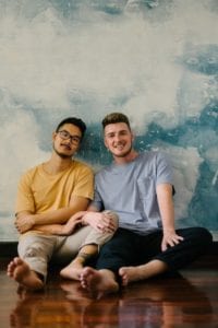Couple sitting on floor leaning towards each other smiling