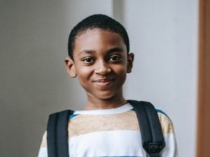 Young child with backpack smiling at the camera